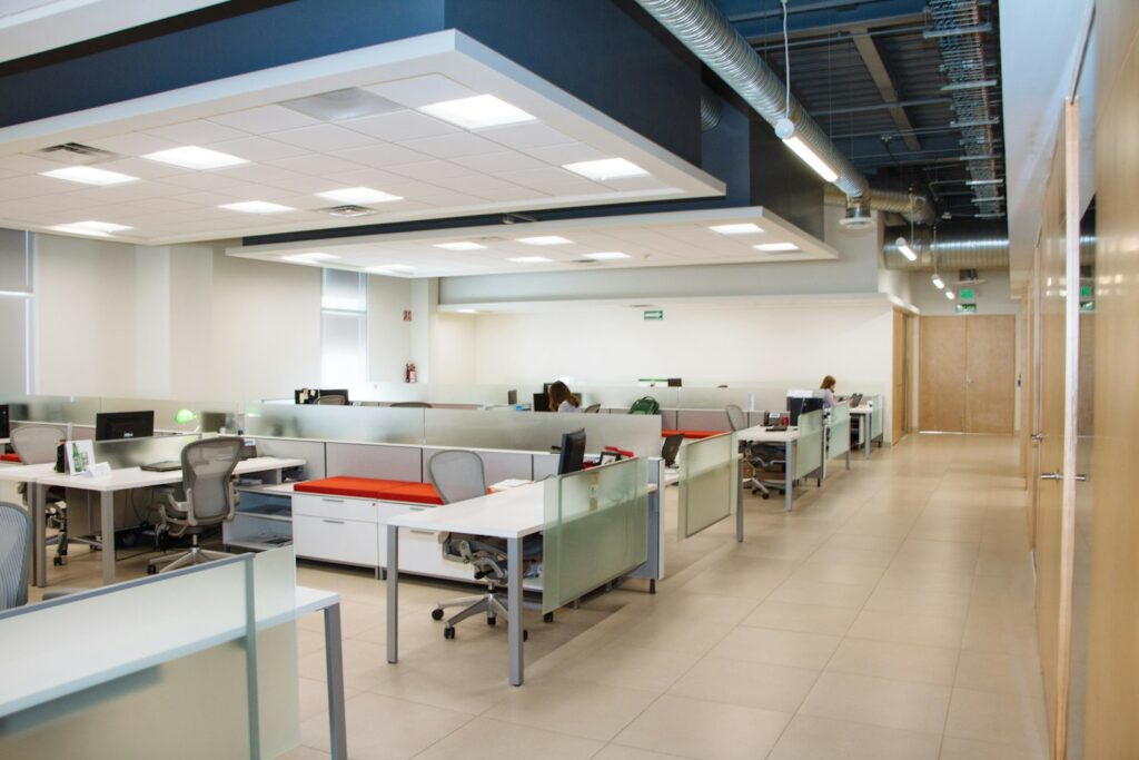 Open-plan office acoustics: workstations with frosted glass partitions and an acoustic ceiling that reduces noise on the floor
